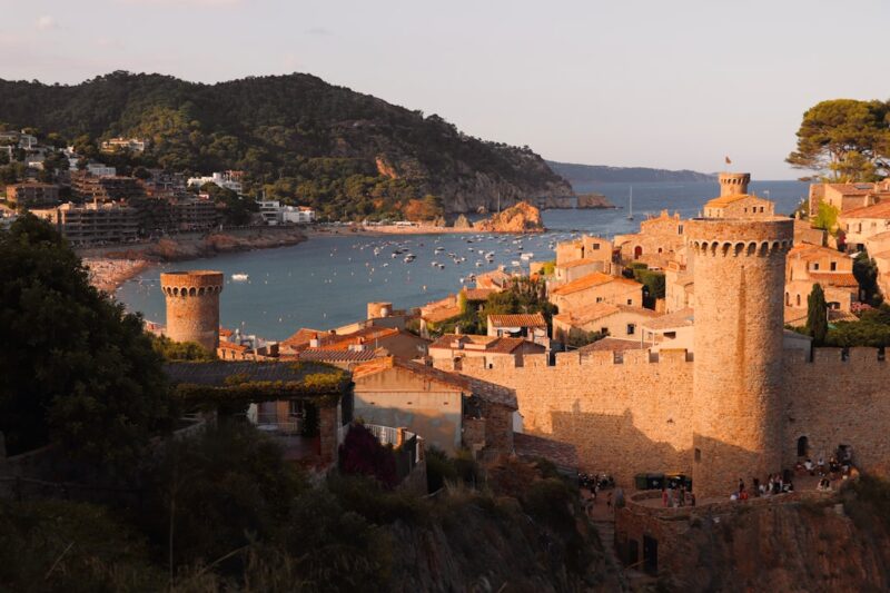 Waar woont Sinterklaas in Spanje volgens de Nederlandse traditie Golden hour over Tossa de Mar on Spain’s Costa Brava: stone medieval towers and crenellated walls watch over a sheltered bay dotted with small boats. Terracotta rooftops, pine-covered hills and calm Mediterranean water capture the warm village atmosphere of Catalonia.