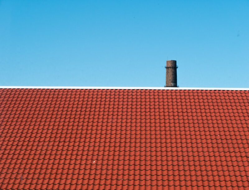Schoorsteen vegen voor het stookseizoen: waarom het nu moet en wat je zelf controleert Gemetselde schoorsteen op een pannendak in het najaar